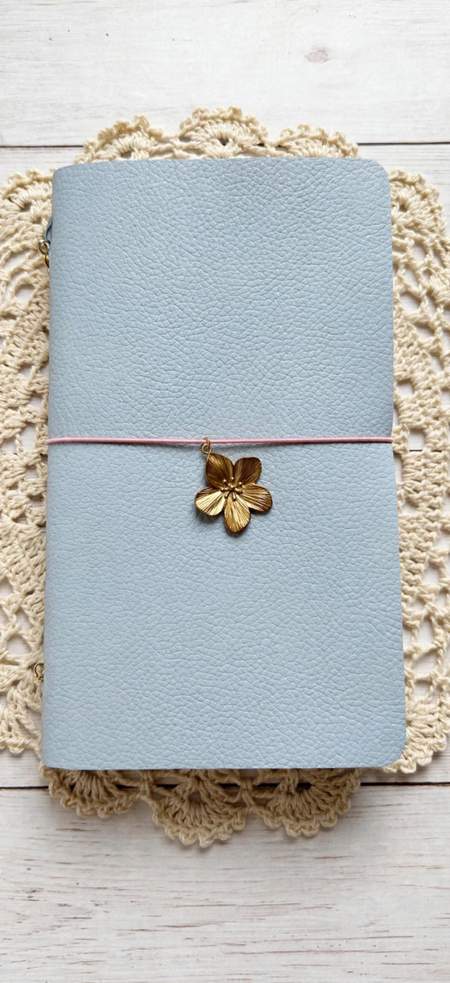 baby blue leather journal with pink elastic cord and gold flower charm