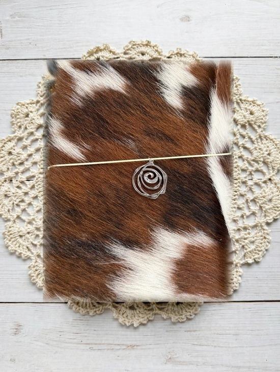 brown and white cowhide journal with silver spiral charm