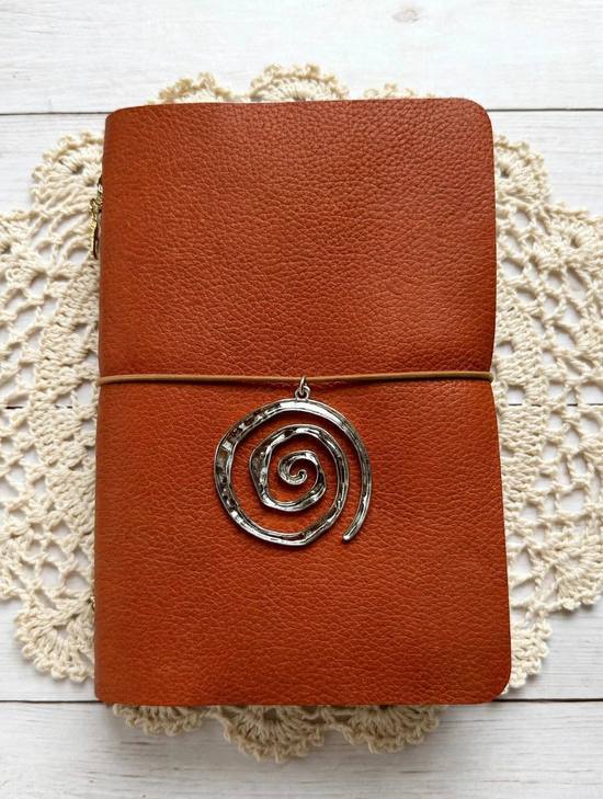 burnt orange leather journal with black elastic and silver spiral charm