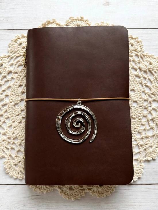 brown leather journal with black elastic and silver spiral charm