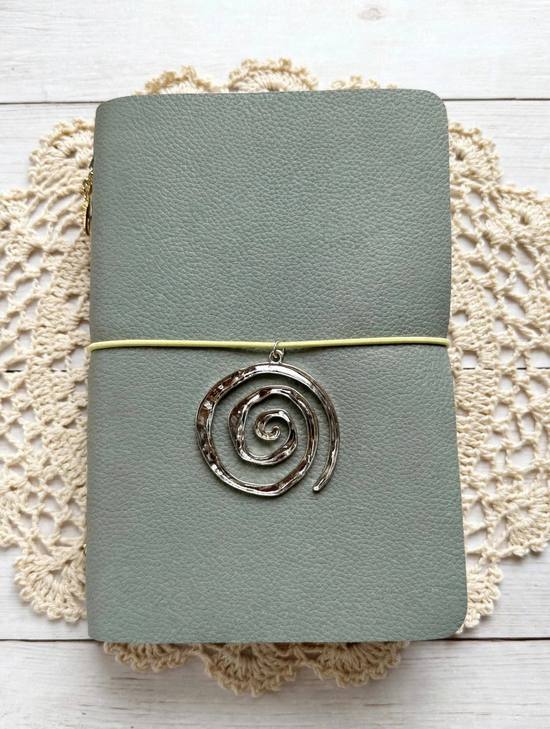 sage green leather journal with black elastic and silver spiral charm